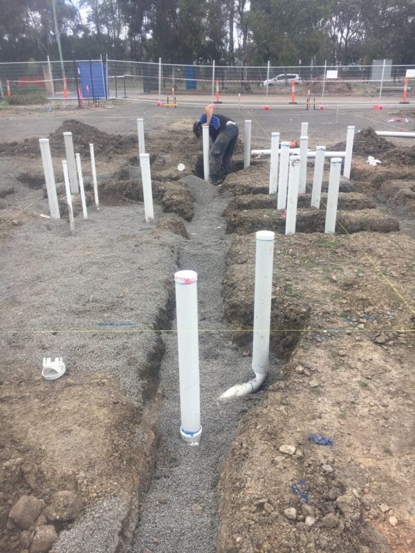 Underground plumbing being installed on an empty lot